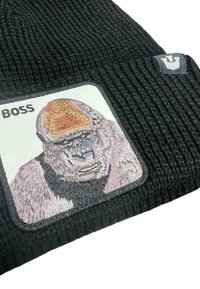 Beanie nero lavorato a maglia con tessuto testurizzato. Presenta una toppa quadrata bianca con un gorilla ricamato e la scritta "BOSS" in grassetto nero.