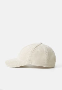 Light beige corduroy cap with a curved brim, six-panel design, visible stitching, and eyelets for ventilation. Simple and textured appearance.