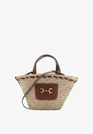 Bolso de mano estilo cesta tejido en beige con asas de cuero marrón, bolsillo delantero, detalle de estribo en tono dorado y una correa de hombro ajustable.