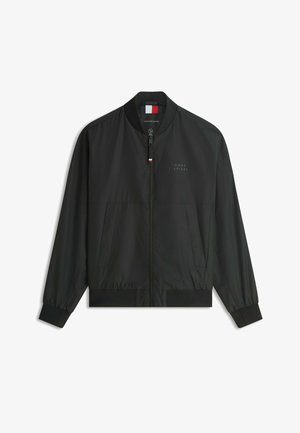 Veste bomber noire zippée avec col, poignets et ourlet côtelés, présentant un logo subtil Tommy Hilfiger sur la poitrine et un petit détail de drapeau sur la fermeture éclair.