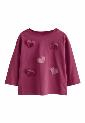 Bordeauxrotes Langarmshirt aus strukturiertem Stoff mit fünf übereinanderliegenden Herz-Applikationen in verschiedenen Rosa- und Weißtönen mit Punkten.