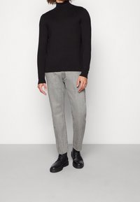 Musta pitkähihaine pooloneule, slim-fit harmaat farkut ja mustat nauhakengät. Sileä pinta, minimalistinen muotoilu ja neutraalit värit.