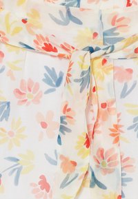 Tejido de flores en colores pastel con una textura suave y transparente. Detalle de lazo en la cintura, con flores rosas, amarillas y azules sobre un fondo blanco.