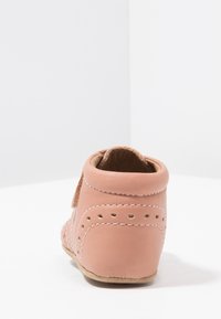 Bota de cuero color marrón claro con punta redonda, que presenta costuras decorativas y acentos perforados alrededor del talón. Ligera y con un acabado suave y texturizado.