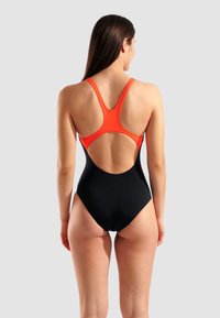 Svart baddräkt i ett stycke med en orange detalj på banden och en öppen ryggdesign. Slät yta och atletisk skärning.