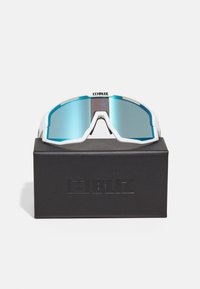 Ochelari de soare sport albi cu un design curbat și lentile reflectorizante albastre, așezați pe o cutie neagră cu un logo debossat.