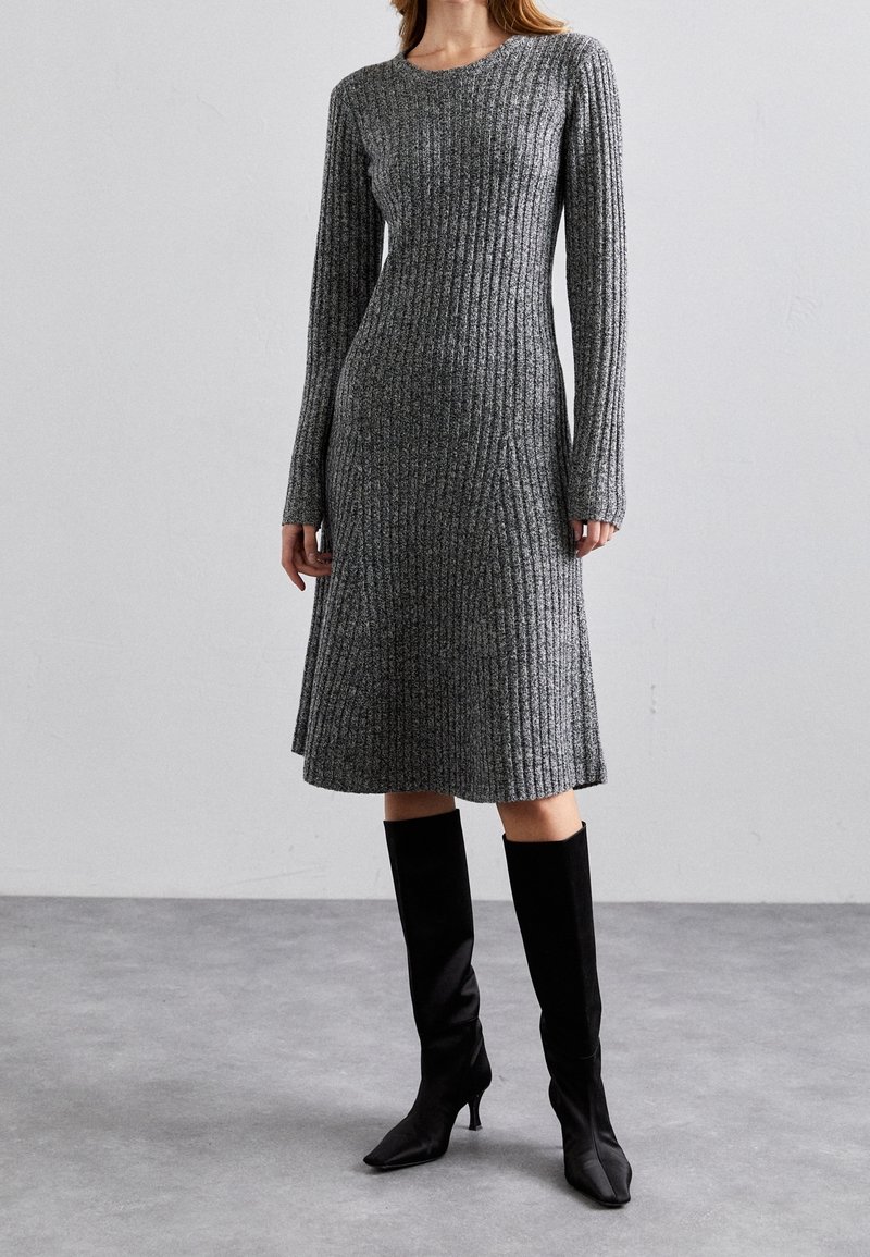 Robe en tricot côtelé gris avec des manches longues, coupe A-line et col rond ; assortie à des bottes noires à talons jusqu'aux genoux.