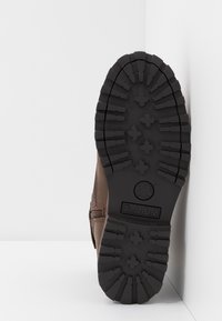Stivale in pelle marrone con suola in gomma texture, dotato di profonde scanalature e logo Timberland. Il tacco è leggermente sollevato.
