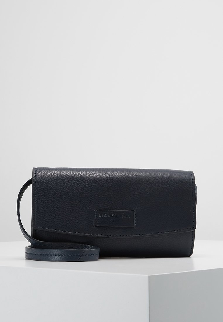 Námořnická kožená crossbody taška s texturovaným povrchem, klopovým uzávěrem a odnímatelným popruhem; na přední straně se nachází diskrétní logo.