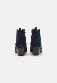 Botas de tobillo de ante azul marino con un acabado texturizado, con cremalleras laterales, un bajo tacón de madera y un diseño de punta redondeada.