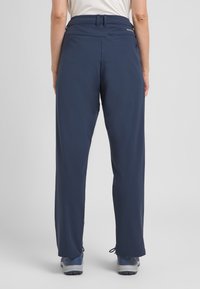 Pantaloni da outdoor in tessuto blu navy con taglio dritto, vita elasticizzata e polsini regolabili; progettati per comfort e mobilità.