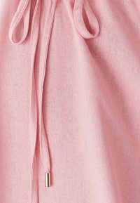 Roze, textiel stof met een trekkoord met een gouden metalen puntgebruik. Het materiaal lijkt zacht en lichtgewicht, geschikt voor casual wear.
