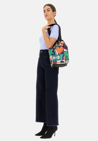 Borsa a tote colorata con motivi grafici, caratterizzata da vivaci tonalità di verde, rosa e blu. Realizzata in tessuto con una texture morbida e dotata di due manici.