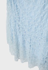 Jasnoniebieska kwiecista koronka o delikatnej, siateczkowej fakturze i falowanym brzegu, miękko ułożona na gładkim tle.