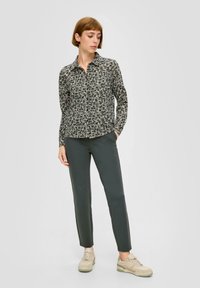Floral long-sleeve shirt in black and cream, paired with dark gray slim-fit pants and cream athletic shoes. Subtle texture and design details.