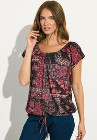 Blusa nera e rosa a fantasia con scollo rotondo, maniche corte, dettaglio arricciato nella parte superiore e un nastro decorativo all'orlo.