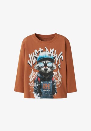 Brązowa koszulka z długim rękawem z grafiką szopa w okularach przeciwsłonecznych i niebieskiej czapce, z tekstem i akcentami górskiego tła. Miękka tkanina.