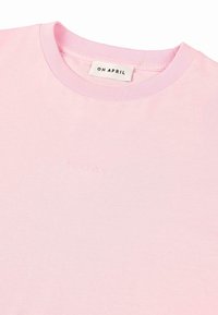 Lys rosa bomulls t-skjorte med rund hals og preget logo "OH APRIL" på brystet. Glatt tekstur, korte ermer.