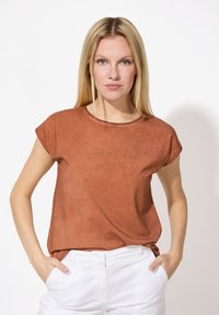Rostfarbendes T-Shirt mit kurzen Ärmeln und Rundhalsausschnitt, mit feiner Textur, verziert mit gesticktem Text "I'M WALKING ON SUNSHINE" in Gold.