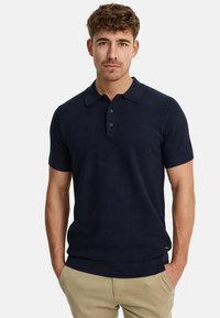 Polo shirt à manches courtes bleu marine fabriqué en tissu tricoté texturé, avec un col et une patte de boutonnage à trois boutons, et un ourlet en rib avec ajustement.