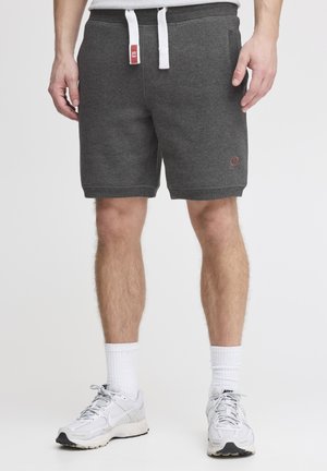 Graue Sweatshorts aus einem weichen Stoff, mit einem elastischen Bund und weißen Kordeln, Seitentaschen und einem kleinen Logo-Detail.