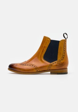 Chelsea-støvle i tanfarvet læder med sort elastisk sidepanel, brogue-detaljer, trækflap og lavt træhæl på hvid baggrund.