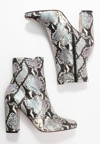 Ankelstövlar i ormskinn med svart, vitt och iriserande blått mönster, fyrkantig tå och en sidodragkedja, med en klumpig klack.