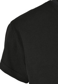 Svart bomulls-T-shirt med rund halsringning och korta ärmar, med en slät yta och synliga sömmar längs fållen.