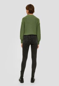 Zielony sweter z dzianiny o teksturowym wzorze, w połączeniu z dopasowanymi, ciemnoszarymi dżinsami i czarnymi, masywnymi butami. Wszechstronny i nowoczesny design.