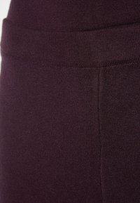 Lila gestrickte Leggings mit glatter Textur und einem breiten elastischen Bund. Hat ein einheitliches Muster und eine körpernahe Passform.