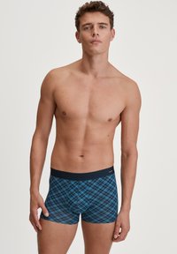 Boxer blu e neri a quadri con una cintura elastica liscia. Il tessuto è morbido, aderente e presenta un motivo a quadretti sulla superficie.