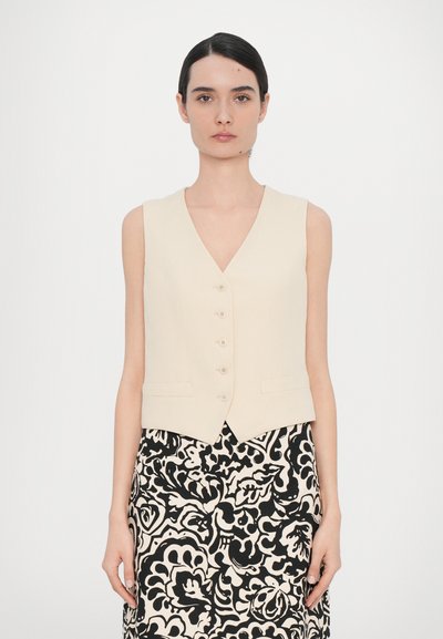 Cream-colored sleeveless vest featuring a V-neck, five buttons down the front, and side pockets, paired with a patterned black and white skirt.