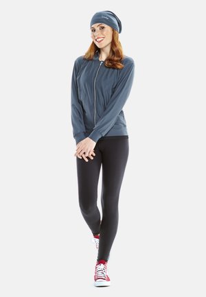 Lightweight blue zip-up jacket paired with black leggings and red sneakers, featuring a smooth texture and simple design.