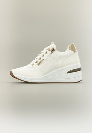 Sneaker zeppa bianco con dettagli dorati, cerniera e tomaia strutturata, mostrato di profilo su sfondo neutro.