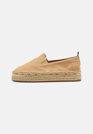 Beige canvas instapper espadrille met dikke gevlochten jute plateauzool en klein stoffen treklusje bij de hiel.