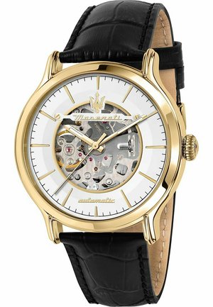 Goldfarbene Automatikuhr mit transparentem Zifferblatt, schwarzem Lederarmband und sichtbar durch das Glasgehäuse blauem mechanischen Uhrwerk.