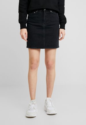 Sort denim nederdel med en tætsiddende silhuet, frontlukning med knapper og fem lommer. Sammen med hvide sneakers for kontrast.