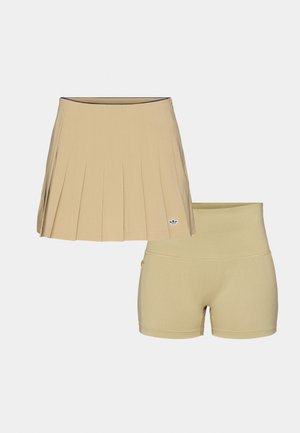 Plekkidega beež seelik, millel on külge õmmeldud beežid lühikesed püksid, valmistatud pehmest kangast. Seeliku servas on tikandiga logo.