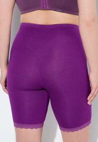 Paarse vormgevende shorts van soepel, rekbaar materiaal met een scalloped kantafwerking aan de zoom, ontworpen voor comfort en bescheidenheid.