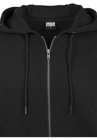 Felpa nera con zip realizzata in tessuto morbido. Dotata di cappuccio regolabile con cordino, zip frontale e dettagli di cucitura. Design semplice e funzionale.