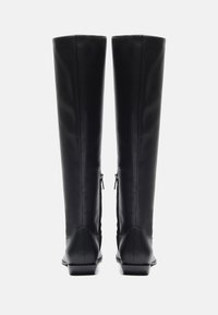 Schwarze knielange Lederstiefel mit glatter Textur, ausgestattet mit einem niedrigen Absatz und seitlichen Reißverschlüssen für ein einfaches An- und Ausziehen. Gerades, schmales Design.