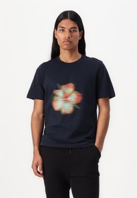Námornícky bavlnený tričko s rozmazaným kvetinovým grafickým dizajnom a bielym textom "LYLE AND SCOTT". S okrúhlym výstrihom, krátkymi rukávmi.