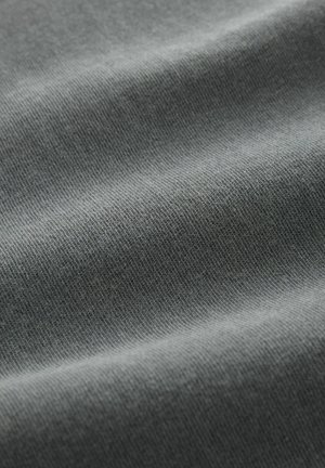 Primer plano de una tela gris con una textura suave, que presenta acanaladuras finas y variaciones sutiles en el tono. Sin patrones ni herrajes visibles.