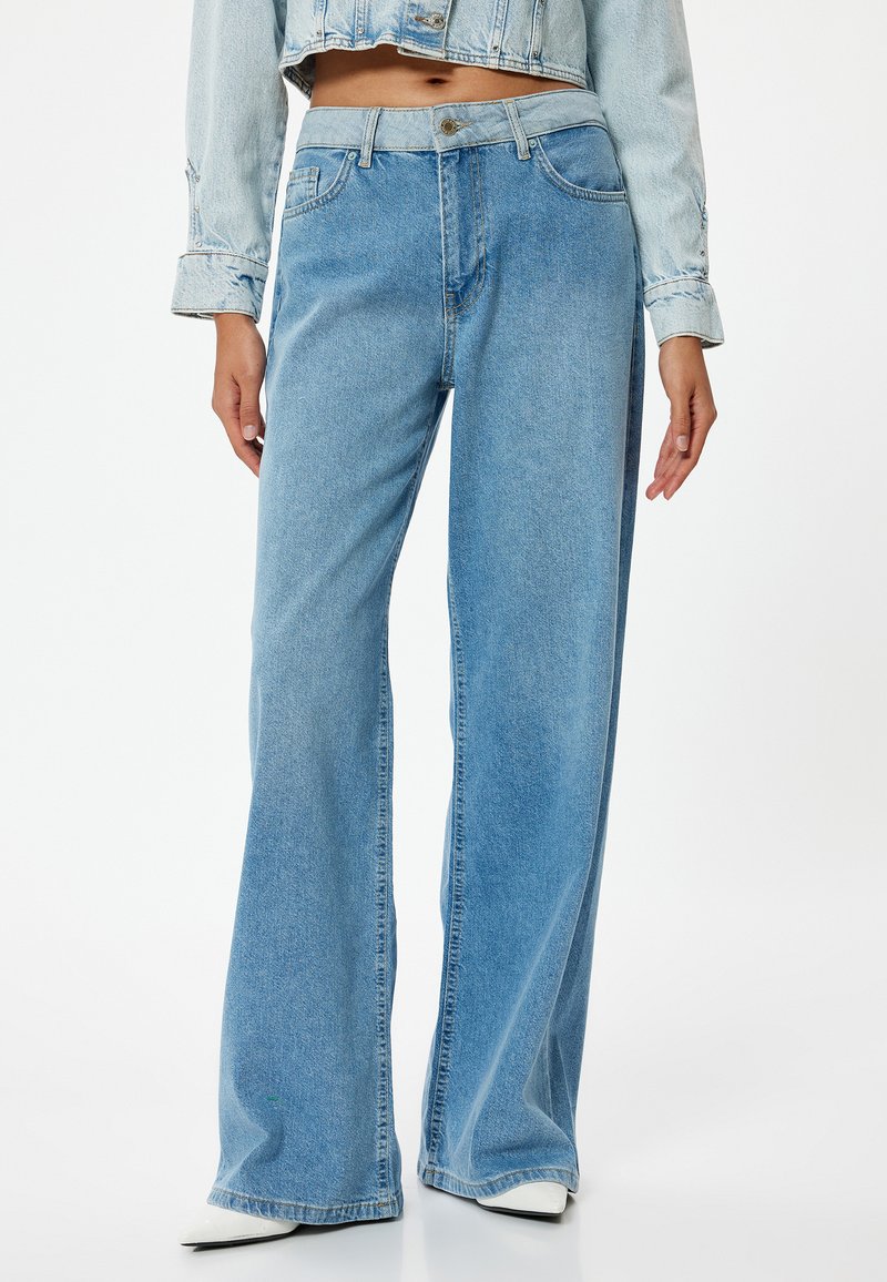 Vaaleansiniset leveälahkeiset farkut denim-kankaasta, joissa on korkea vyötärö, etutaskut ja hillitty haalistunut pinta.