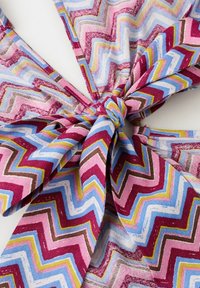 Material moale cu model zigzag multicolor legat într-un nod central, cu nuanțe de roz, albastru, galben, alb și maro.