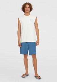 White sleeveless t-shirt with a blue logo, paired with blue shorts and black flip-flops; simple design and casual style.
