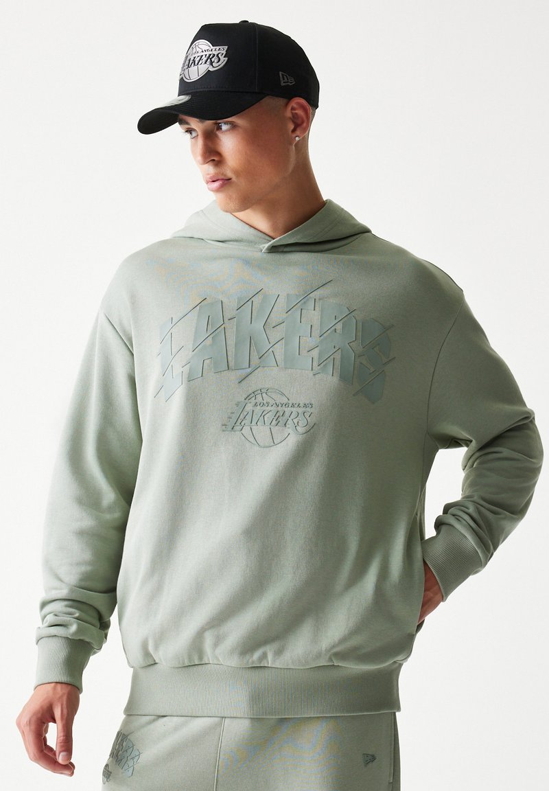 Ανοιχτό πράσινο φούτερ με κουκούλα και ανάγλυφο σχέδιο των Los Angeles Lakers. Διαθέτει εφαρμοστή μέση και κουκούλα. Μαύρο καπέλο με το λογότυπο των Lakers.