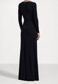 Långärmad, figurnära klänning i mörk marinblå, tillverkad av ett glatt tyg. Har en dold dragkedja på baksidan och en golvlång design. Enkel silhuett.