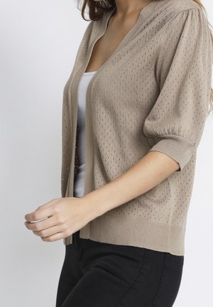 Beige knitted cardigan with a textured pattern, short sleeves, and ribbed cuffs. Features an open front and a relaxed fit.