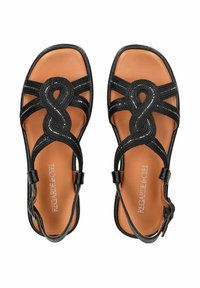 Schwarze geflochtene Sandalen mit einem zentralen Knotendesign, ausgestattet mit einem hellbraunen Fußbett und verstellbarem Knöchelriemen. Glatte Textur und geometrische Form.